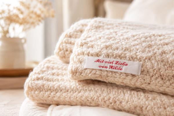 White cotton label with red lettering on knitted blanket