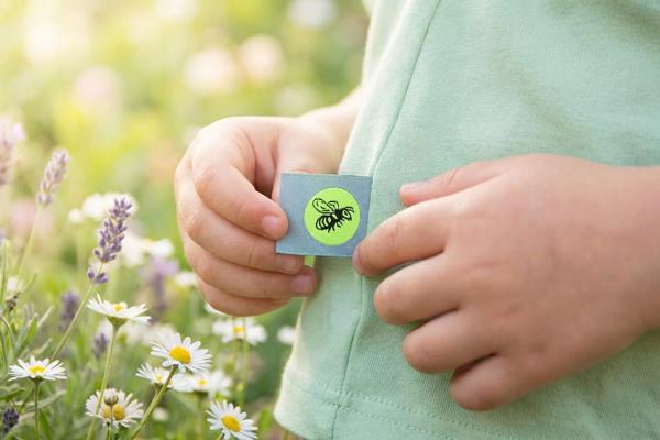 Light blue folded label with bee motif sewn into a children's shirt seam